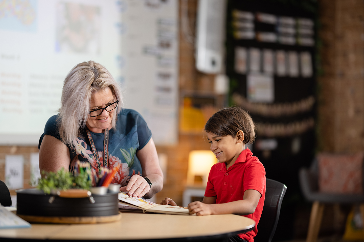 Female teacher reading a book to a young learner