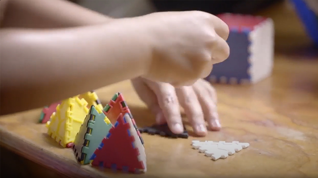 A close-up of a learner’s hands building 3D shape models.